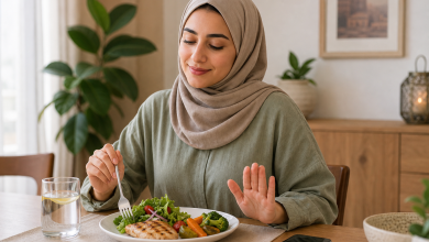 امرأة محجبة تجلس أمام طبق طعام صحي وتستعد للأكل على مائدة منزلية